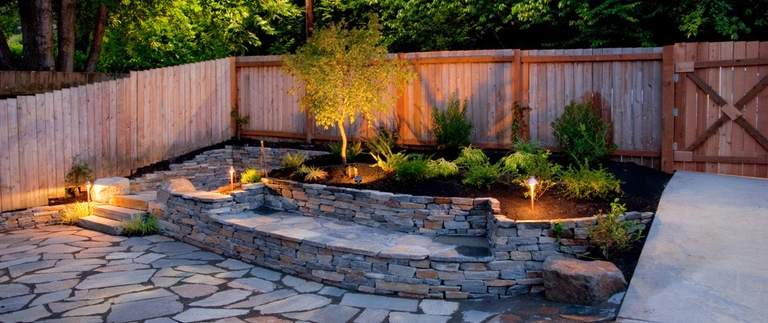 A custom built seating wall with lighting and landscaping surrounding it at a home in Nazareth, PA.