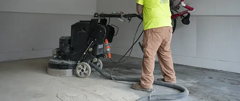 Man prepping the concrete surface for epoxy coating